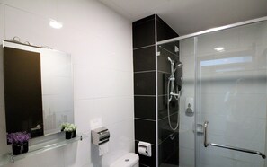 A modern bathroom with a glass shower enclosure, a toilet, a hand dryer, and a small potted plant. - H2H Marine Home (Ipoh)