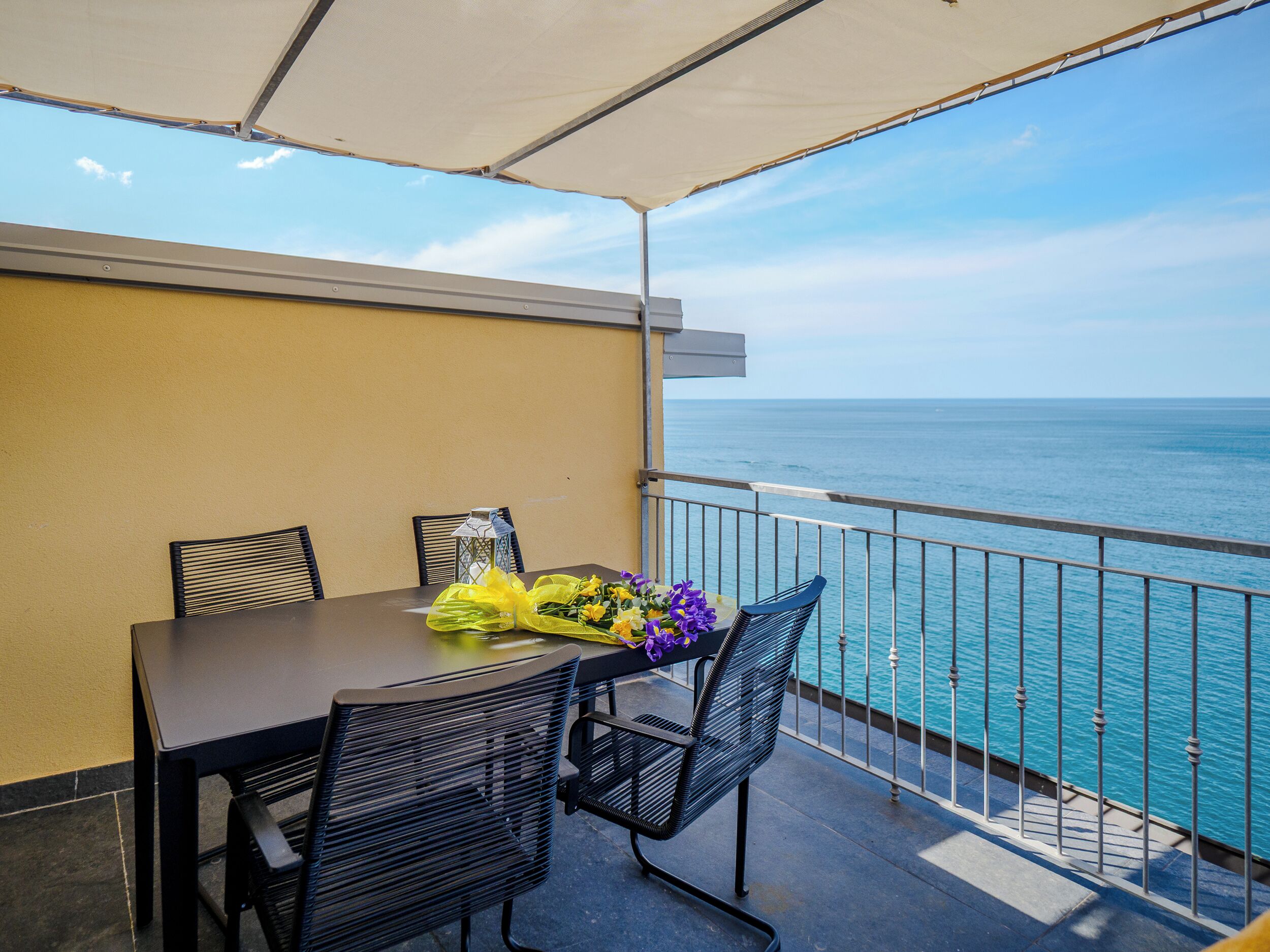Ein Balkon mit Tisch und Stühlen mit Blick auf ein Gewässer.