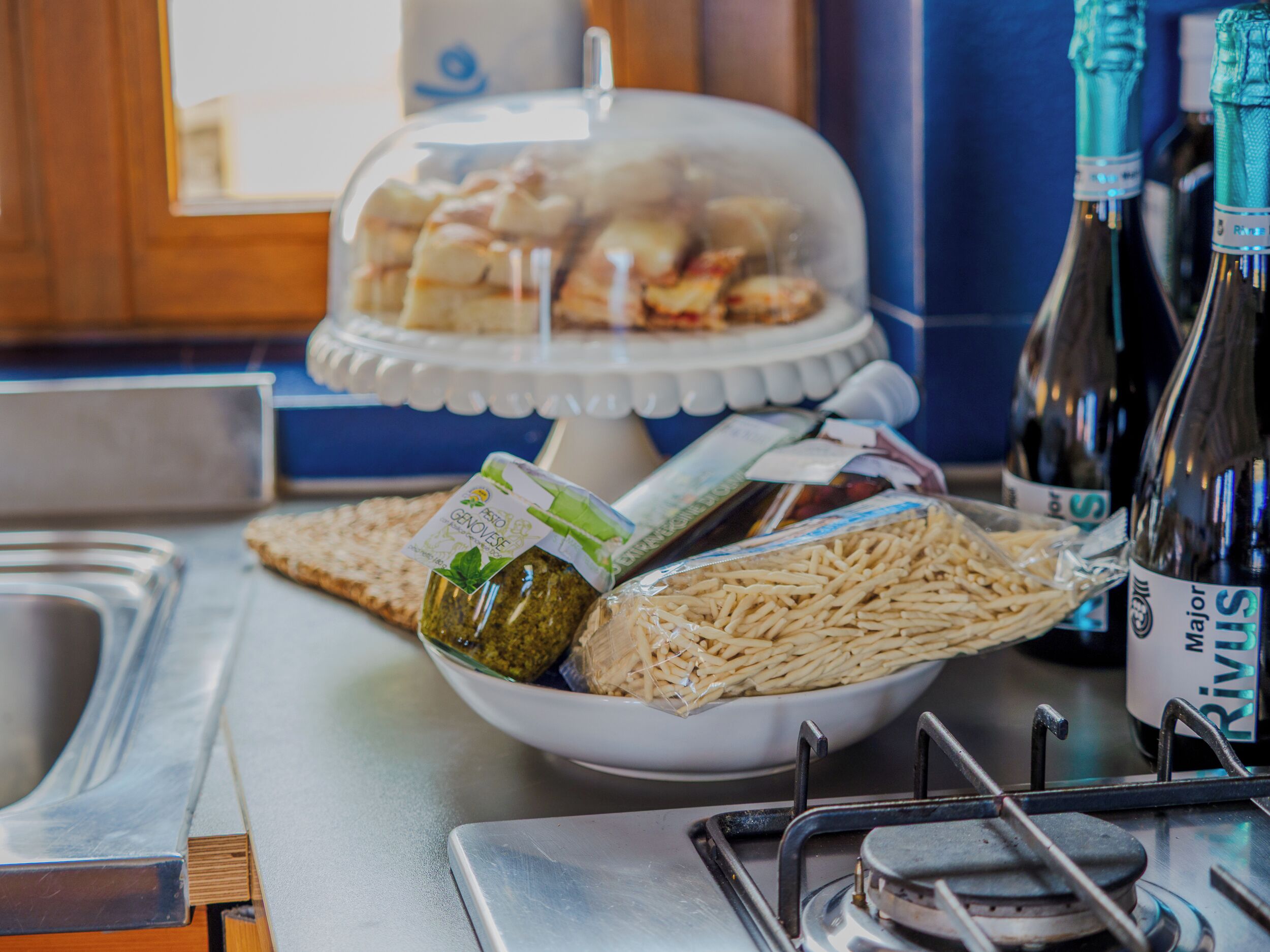 Un buffet proposant une variété de plats, notamment des pâtes, du pain et un présentoir à desserts couvert.