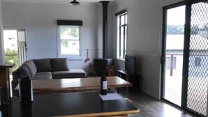 A modern kitchen with a wooden island, a dining area with a sofa, and large windows providing natural light.