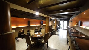 A restaurant with booths and tables, wooden pillars, and a warm ambient lighting. - Bhimaas Temple Tree (Chennai)