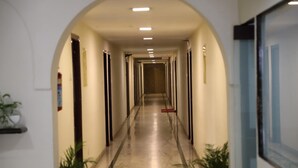 A long, narrow hallway with a marble floor, flanked by columns and potted plants. - Bhimaas Temple Tree (Chennai)