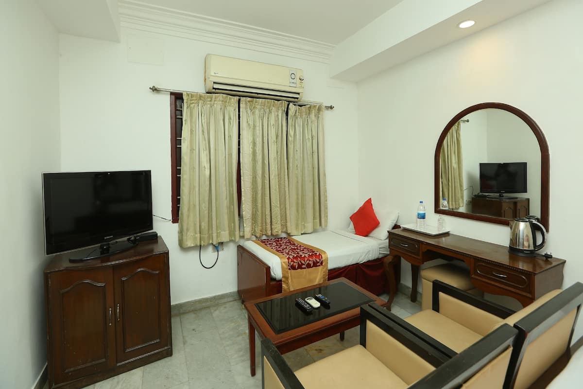 A hotel room with a bed, a TV, a desk with a mirror, a coffee maker, and a sofa.