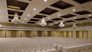 A large, well-lit hall with rows of white chairs and ornate chandeliers. - Bhimaas Temple Tree (Chennai)