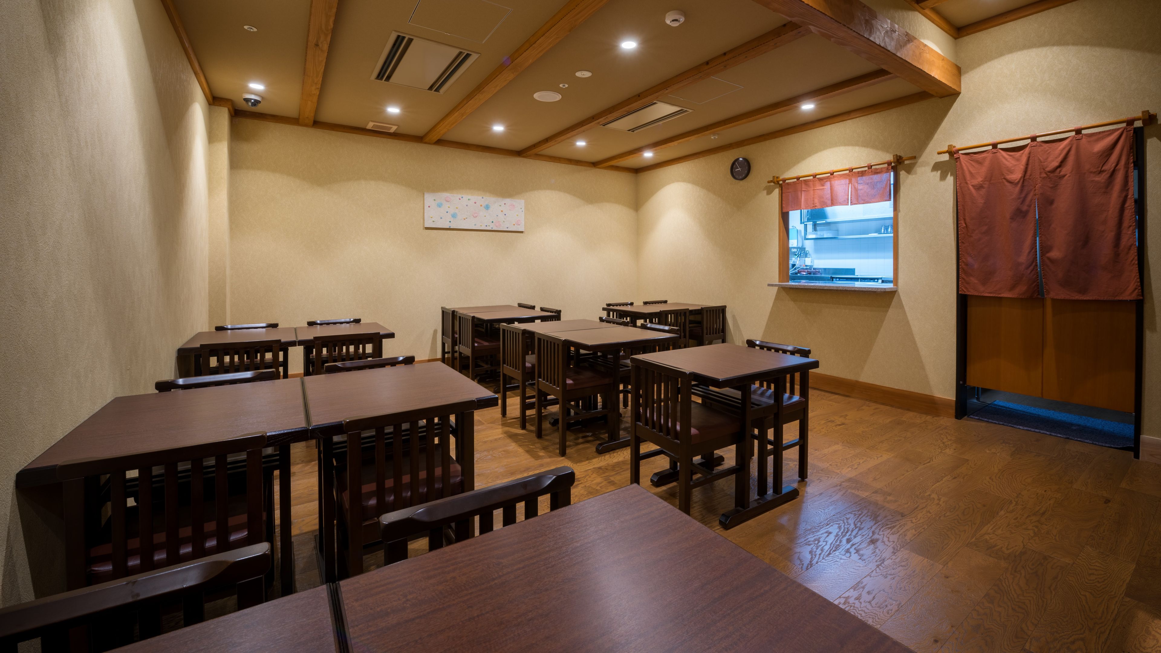 A room with multiple wooden tables and chairs, a clock on the wall, and a window with a view.
