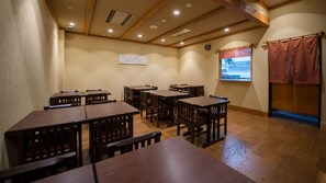 A room with multiple wooden tables and chairs, a clock on the wall, and a window with a view.