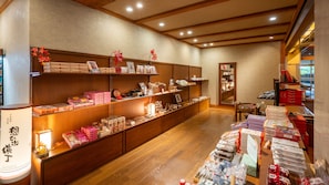 A traditional Japanese shop interior with wooden shelves displaying various packaged goods and a counter with more items.