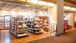 Una tienda bien iluminada con varias estanterías llenas de productos, un mostrador refrigerado y un piso de madera.