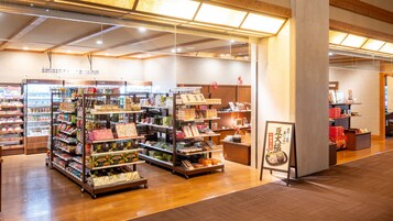 Una tienda bien iluminada con varias estanterías llenas de productos, un mostrador refrigerado y un piso de madera.