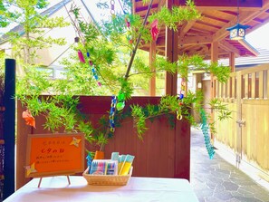 A wooden pergola with a woven basket containing stationery items, a sign with Japanese text, and a bamboo plant. - Naruko Onsen Yumoto Kissho (Osaki)