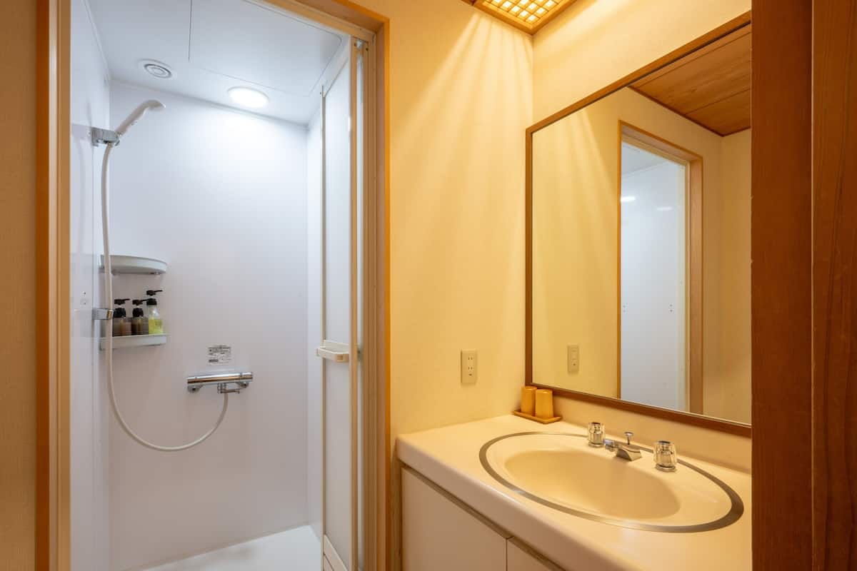 Un baño con ducha, lavamanos y espejo.