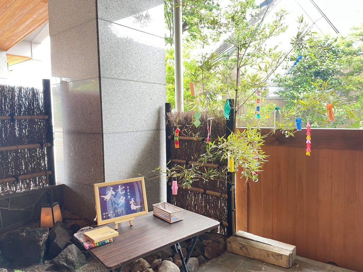 A stone pillar, a wooden table with a framed picture, and a small plant.