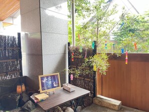 A stone pillar, a wooden table with a framed picture, and a small plant.