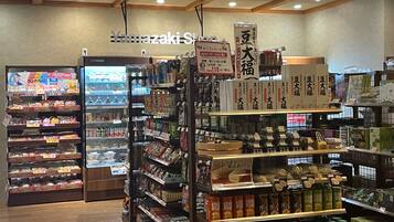 A grocery store interior with shelves stocked with various products, a refrigerated section, and a sign for Yamazaki Store.