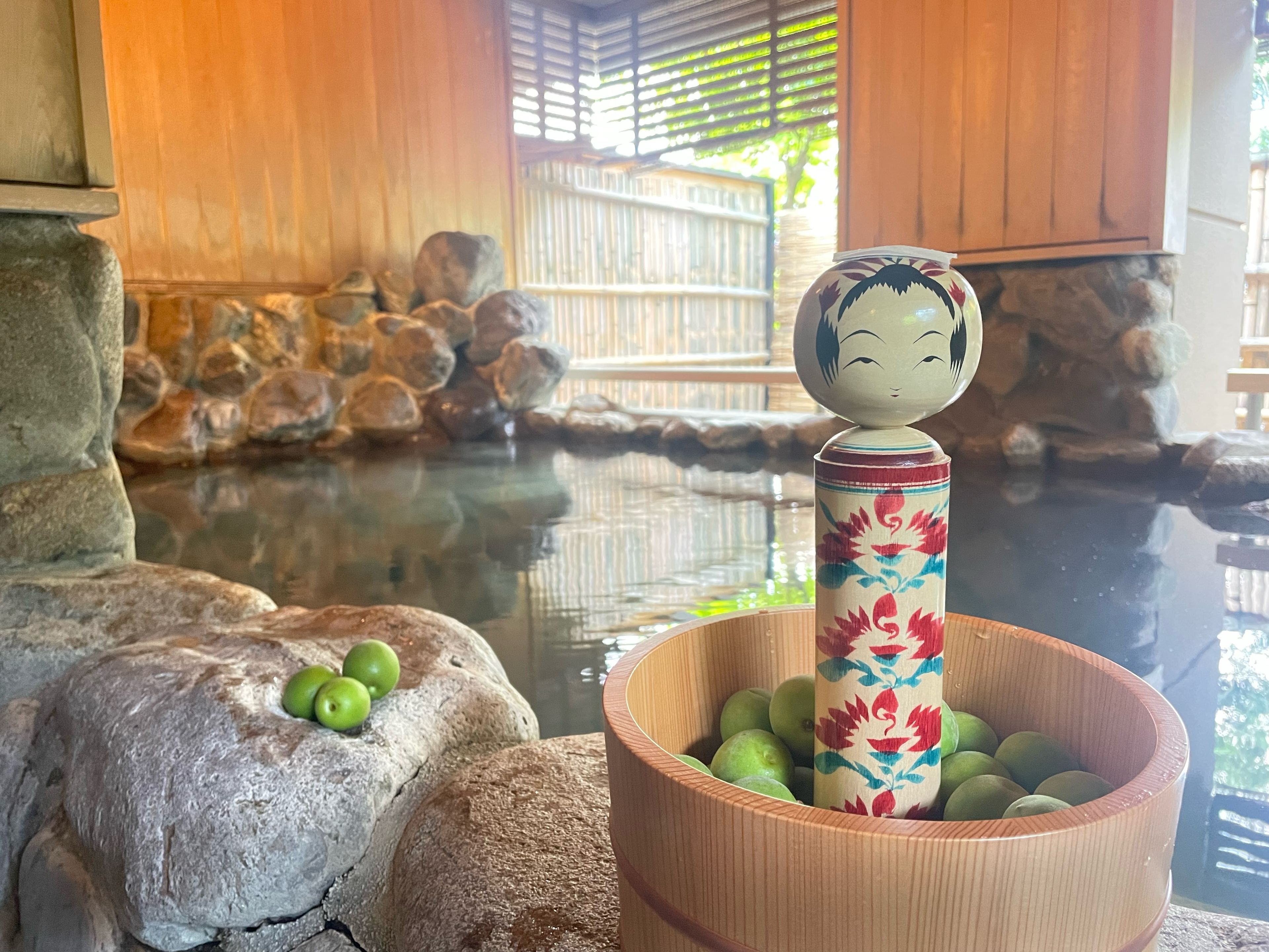 A traditional Japanese garden with a koi pond, a wooden statue, and a decorative bowl with green apples.