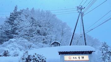 A snow-covered sign with Chinese characters, surrounded by trees and power lines.