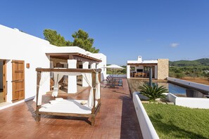 A modern outdoor patio with a wooden bed, a pool, and a dining area.