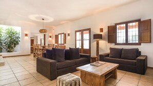 A spacious living room with two sofas, a coffee table, and a dining area with chairs and a table. - Villa Dalt S'Era - Free week from July 13 to 20 (Santa Eulària des Riu)
