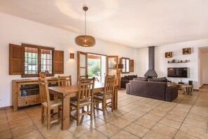 A spacious living area with a dining table and chairs, a sofa, and a television.