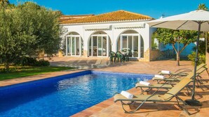 A swimming pool with lounge chairs and a building with arched windows. - Villa Garlanda - PlusHolidays (Benissa)