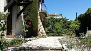 A stone pathway leading to a rustic building with a stone staircase and a metal railing.