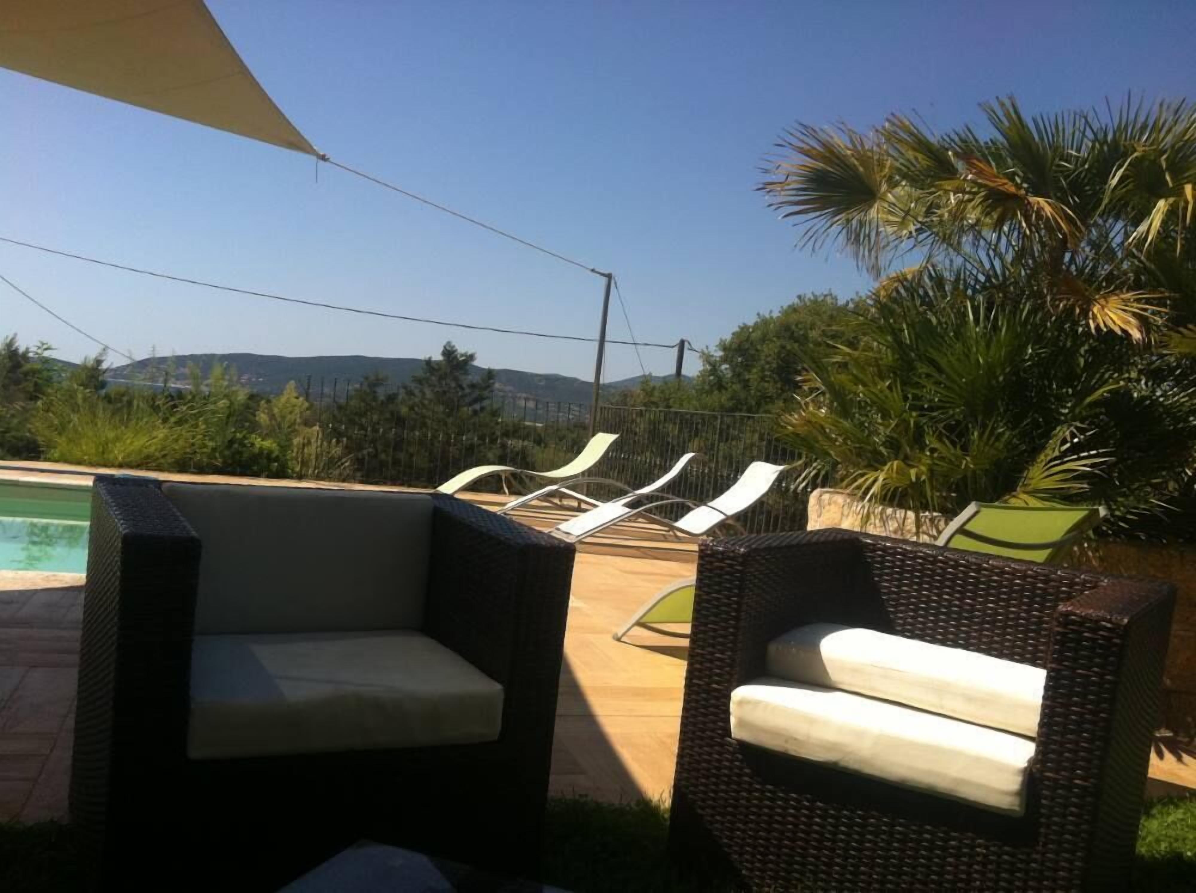Une terrasse avec des meubles en osier et une piscine.