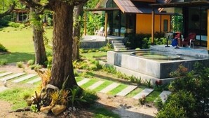 A modern building with a sloped roof, surrounded by lush greenery and a well-maintained garden.