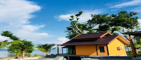 A beachfront property with a yellow building, a covered outdoor seating area, and a view of the sea.
