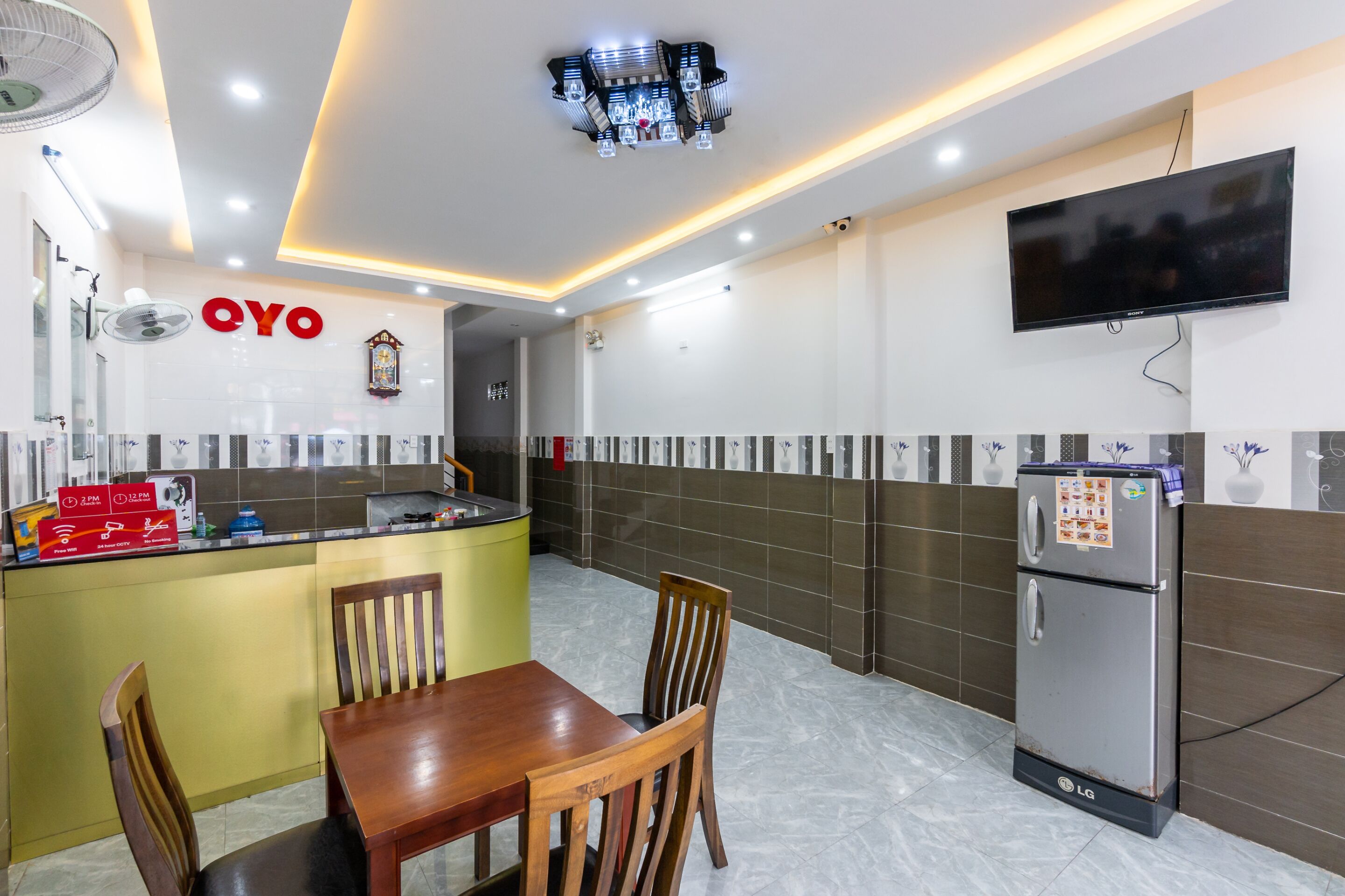 A modern kitchen with a dining area, a refrigerator, and a flat-screen TV.