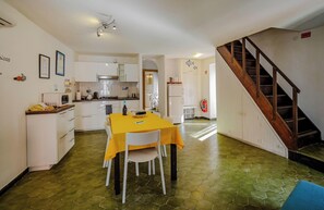 A kitchen with white cabinets, a yellow table, and a staircase.