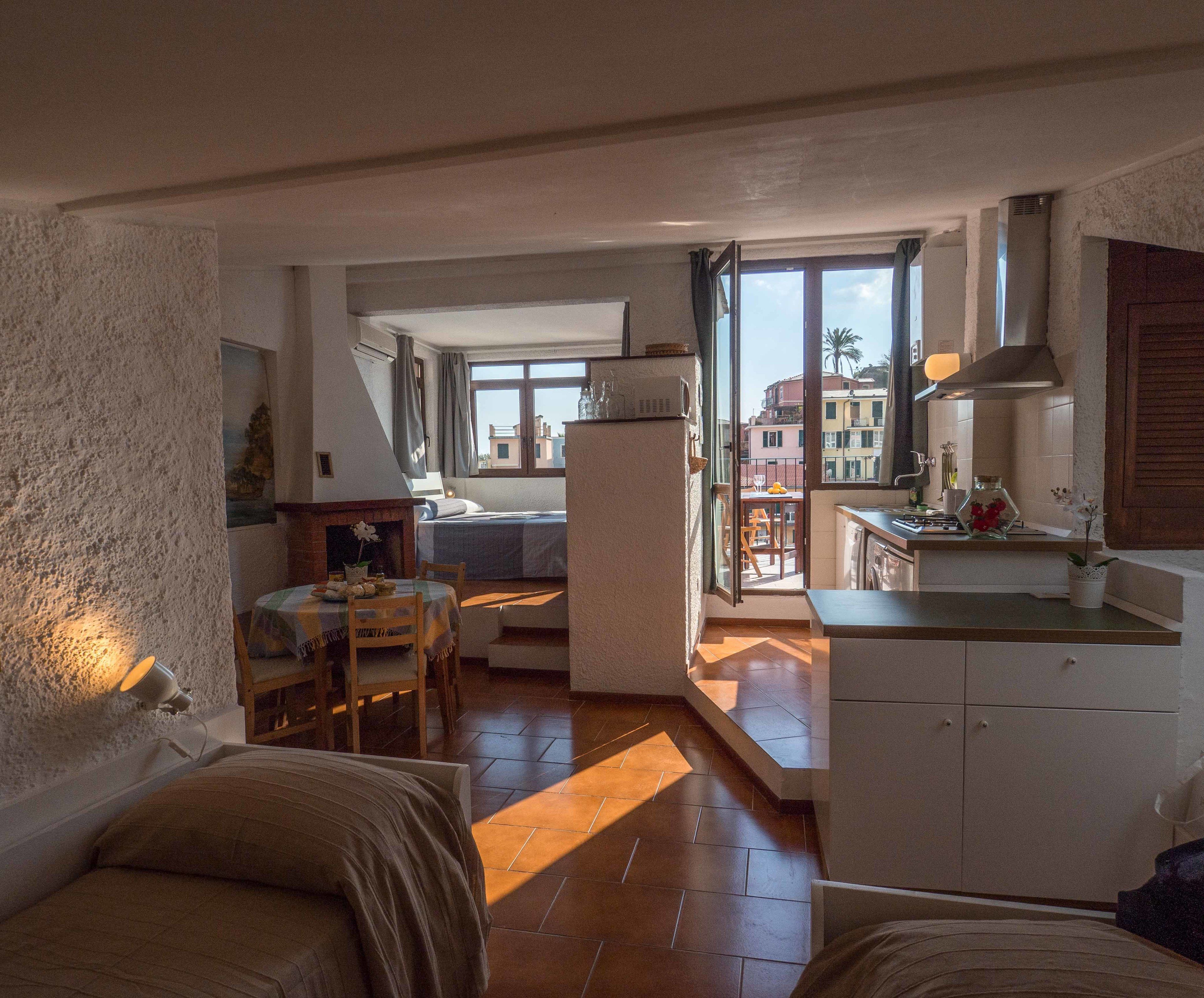 A compact living space with a kitchenette, a dining area, and a bedroom with a view.