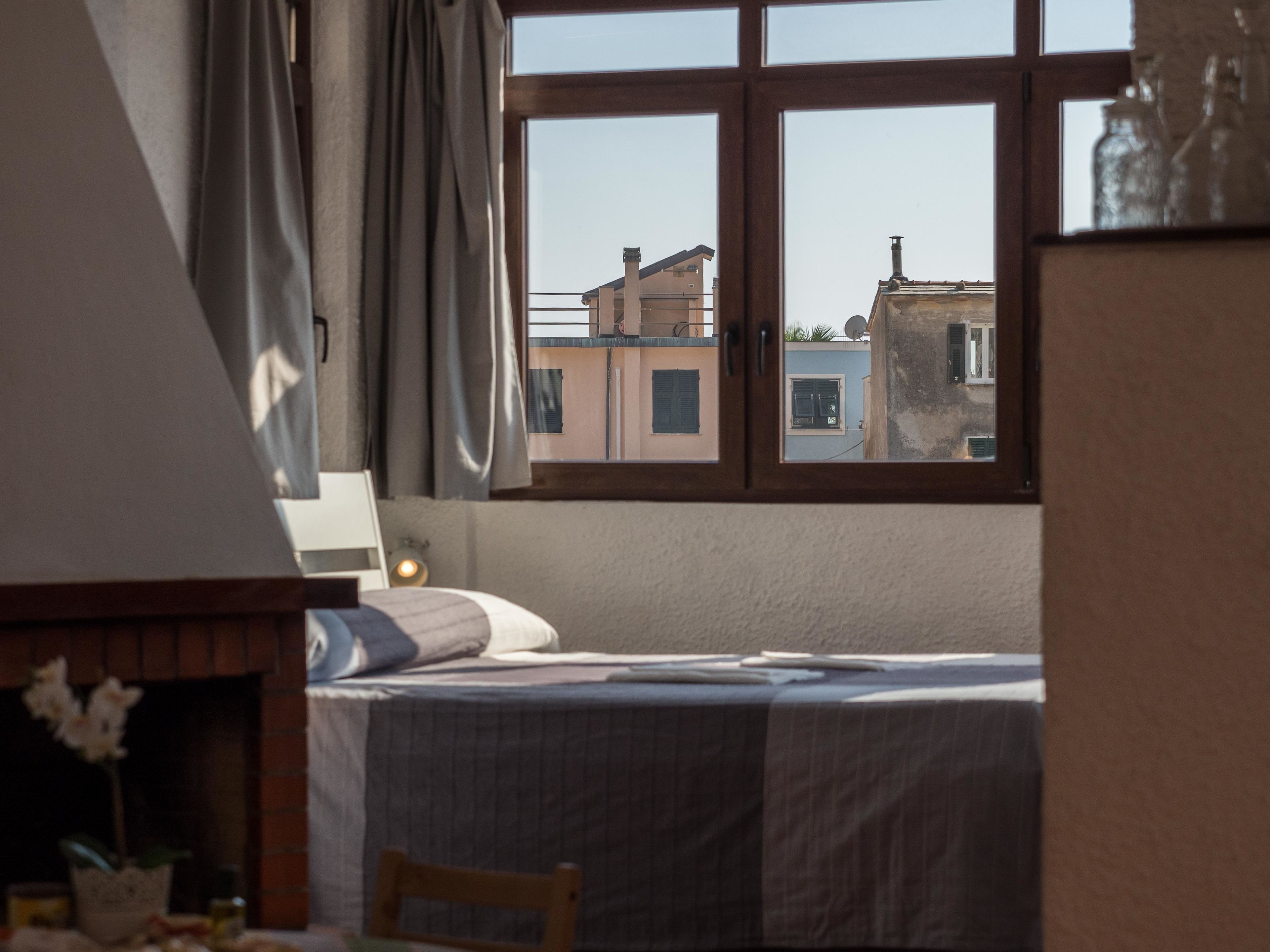 A bedroom with a bed, a window, and a view of buildings outside.