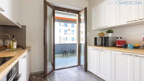 A modern kitchen with white cabinets, a wooden countertop, and a view of an outdoor balcony. - ClickSardegna Penthouse Valencia with Sea-View Terraces, Close to the Beaches (Alghero)