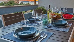 A table set for dining with a view of a sunset and a building in the background. - ClickSardegna Penthouse Valencia with Sea-View Terraces, Close to the Beaches (Alghero)