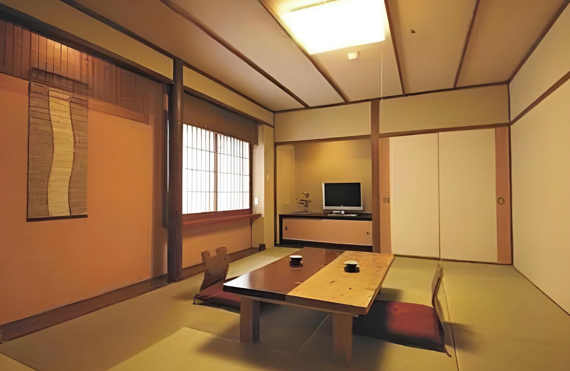 A traditional Japanese-style room with tatami flooring, a low table, and a television on a stand.