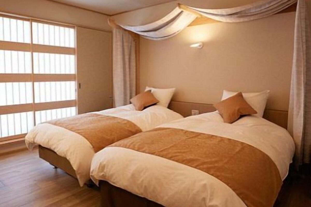 Habitación de hotel con dos camas, un ventanal amplio y un diseño moderno en el techo.