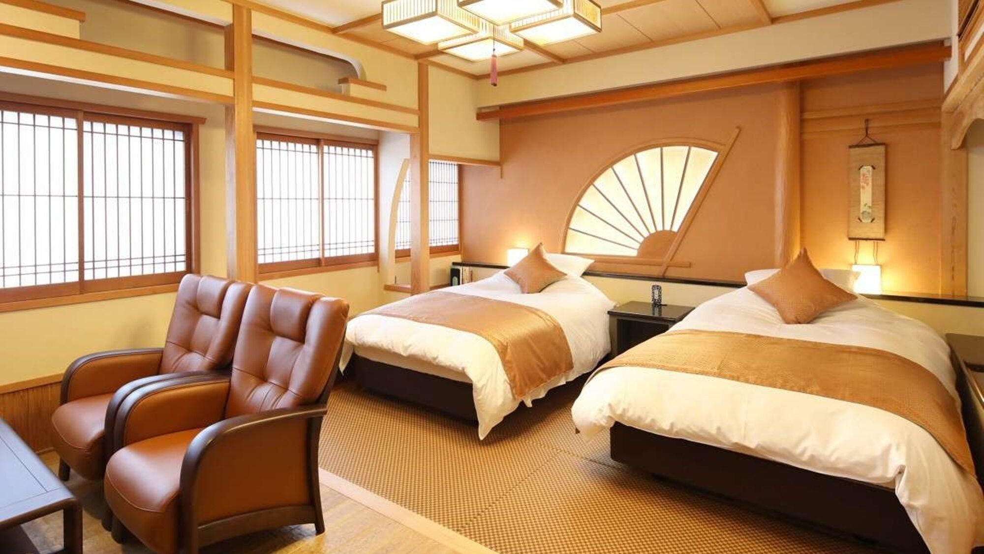 Habitació d'hotel de planta japonesa tradicional amb fons de tatami, dos llits amb capçals a joc, una cadira de cuir marró i un panell shoji.