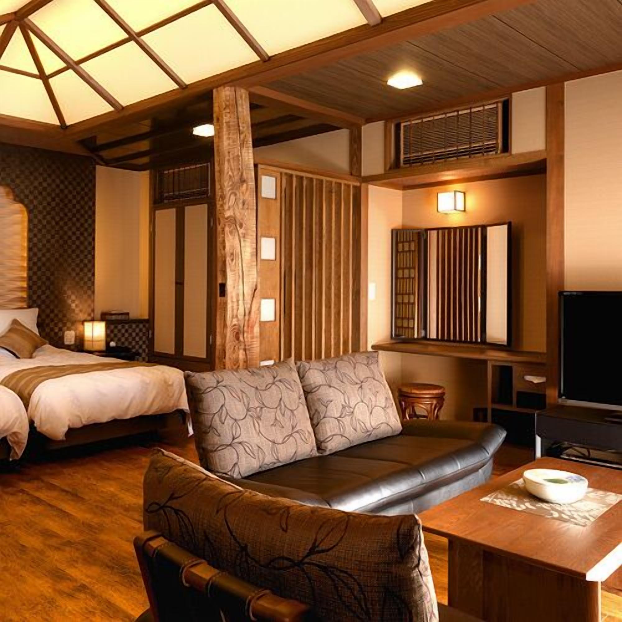Una habitación de hotel con cama, sofá, televisión y techo de madera.