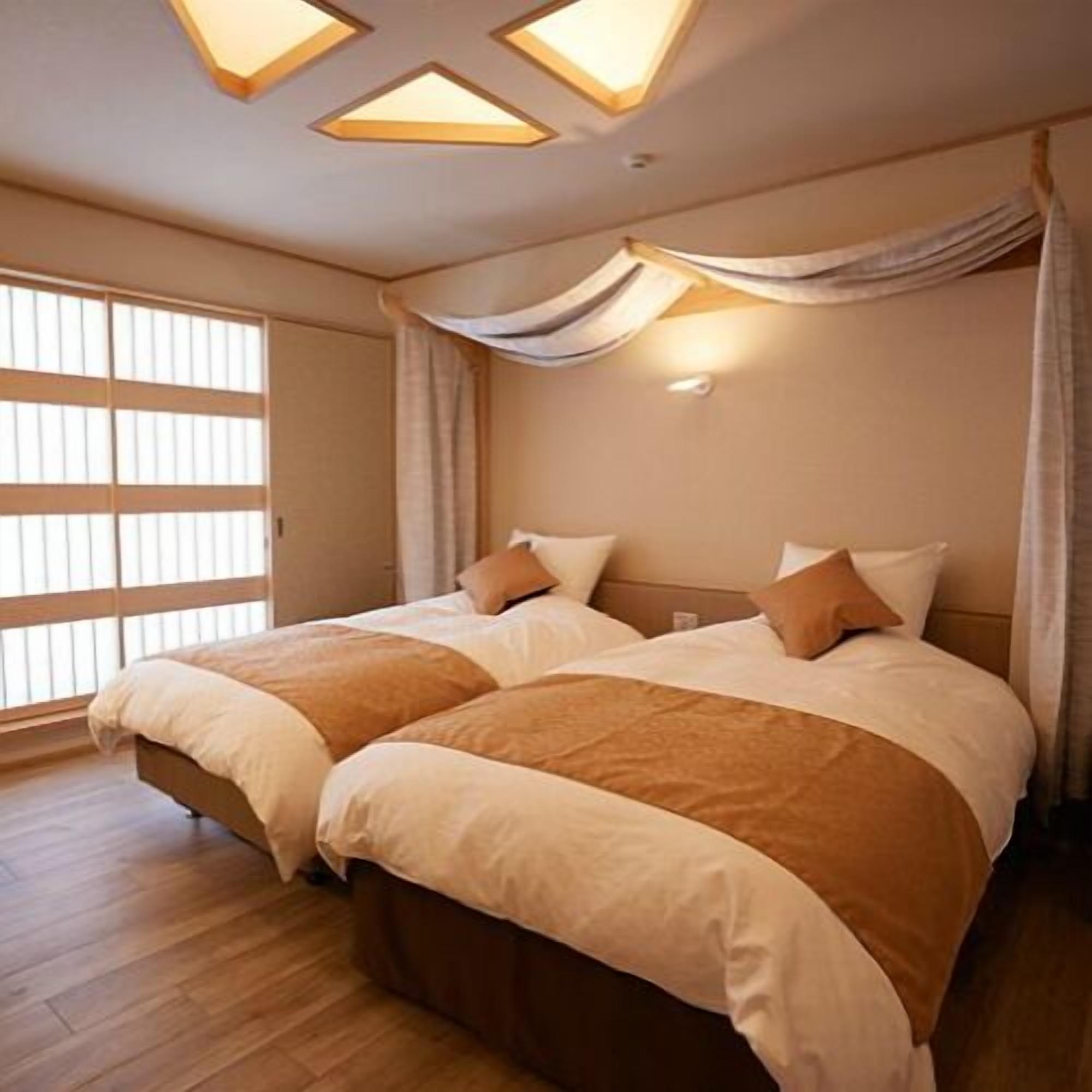 Habitación de hotel con dos camas, un ventanal amplio y un diseño moderno en el techo.