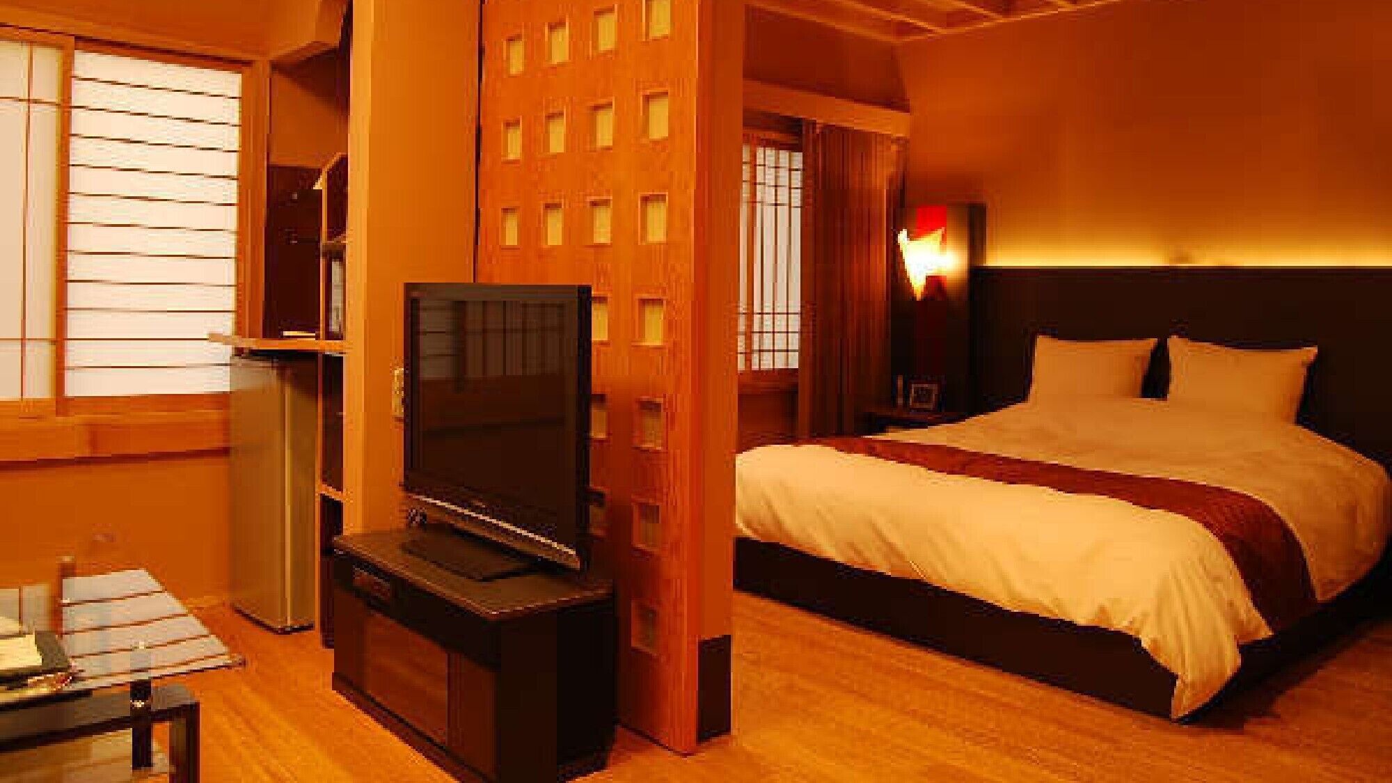 Una habitación de hotel con cama, televisión, escritorio y ventana con persianas.