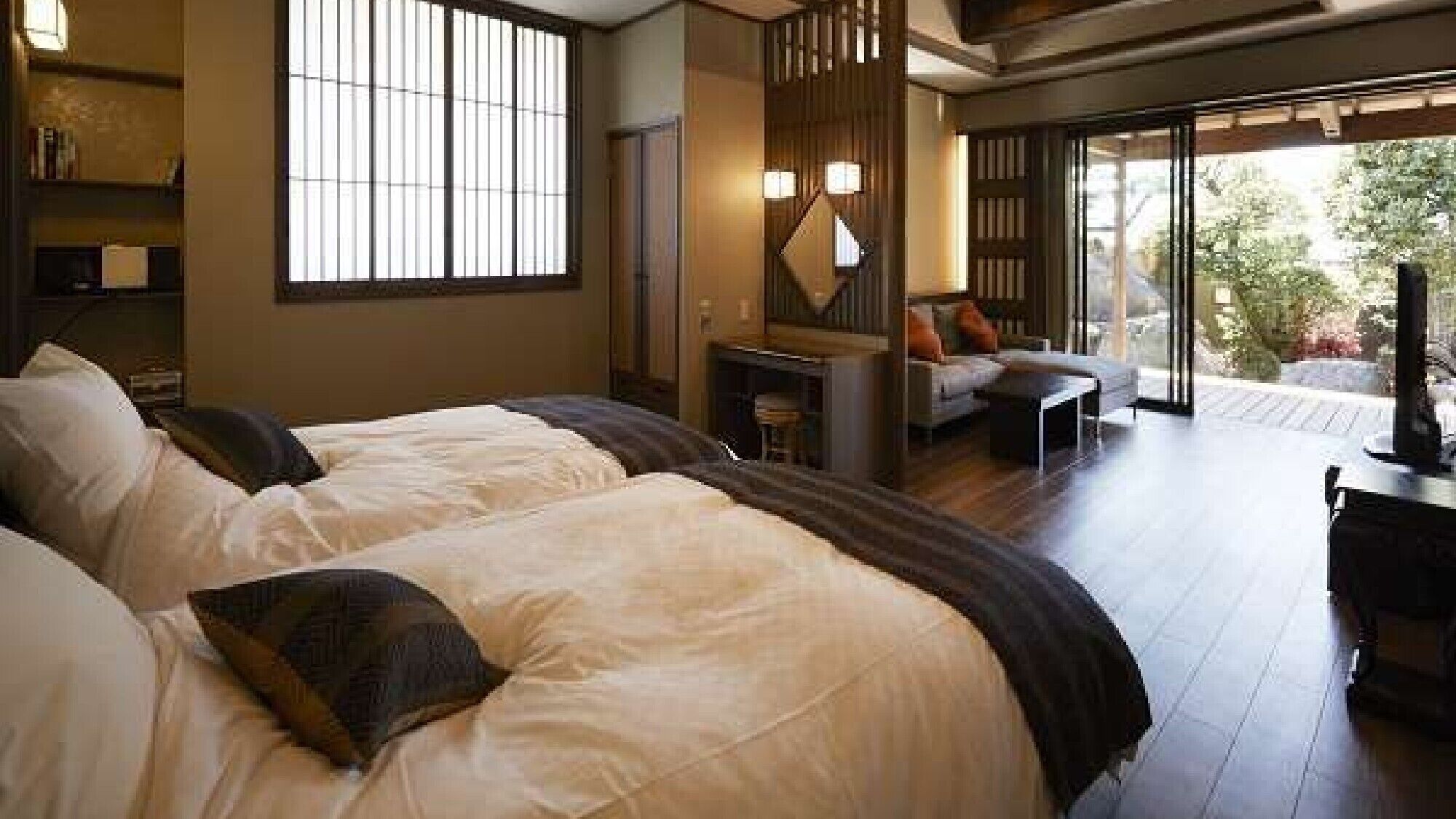 Habitación de hotel con dos camas, un sofá, un televisor y un ventanal corredero al exterior.
