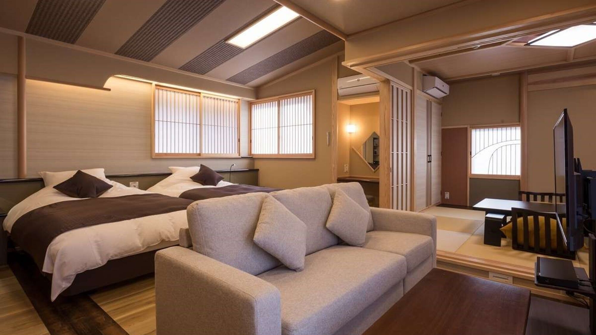 Una habitación de hotel con cama, sofá, televisor y escritorio.