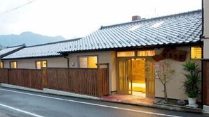 Uma casa japonesa tradicional com telhado de telhas, cerca de madeira e pequena entrada.