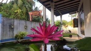 A water feature with a large pink flower in the foreground, a sign reading "Senu Villa", and a covered outdoor area with columns and a view of the surrounding greenery. - senu villa (Bope-Poddala)