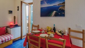 A dining area with a table set for four, a red tablecloth, and a painting of a coastal landscape. - Il Baluardo Sea View Apartment on the Cliff (Riomaggiore)