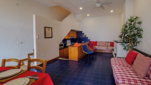 A spacious living area with a dining table set, a sofa, a staircase leading to a kitchen, and a ceiling fan. - Il Baluardo Sea View Apartment on the Cliff (Riomaggiore)
