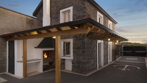 A stone building with a covered patio area, a fireplace, and a bike parking symbol on the ground. - Casa do Leme - Rustic House (Funchal- Madeira)