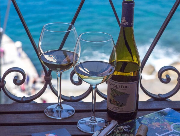 A bottle of wine and two glasses on a table with a view of the ocean.