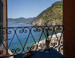 A balcony with a view of the sea, a bottle, and two glasses on a table. - Ventegà Sea View Apartment with Balcony (Vernazza)