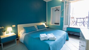 Quarto com cama, mesas de cabeceira, janela com vista e um cabideiro.